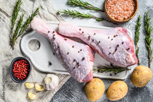 Raw Turkey leg with spices on a white cutting Board. Gray background. Top view