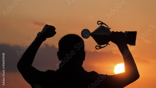 Silhouette best man Winner Award victory trophy for professional champion challenge holding trophy cup over head with success in goal. Concept as victory, success and champion in sport. photo