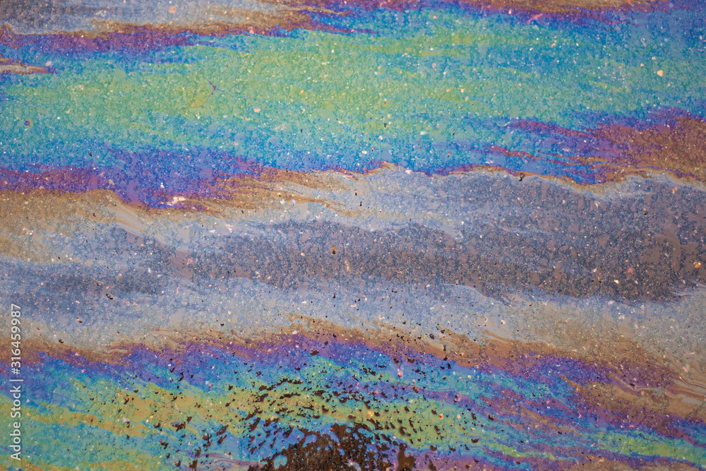 Spilled fuel. A beautiful multi-colored spot. Gasoline stains on the surface. Bright acid colors. Abstract texture. All colors in one fuel spot. Gasoline crisis.