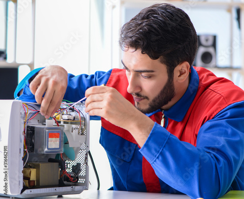Young repairman fixing and repairing microwave oven