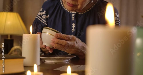 Portrait of old Caucasian witch holding coffee cup and reading fate. Senior woman telling destiny using coffee grounds. Divination, tasseography, prediction. Cinema 4k ProRes HQ. photo