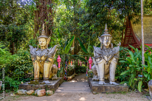 Buddha Statue in the Woods at the  Buddhist Wat Palad Pha Lat Wat Sakithaka Forest Temple in Chiang Mai Province Thailand photo