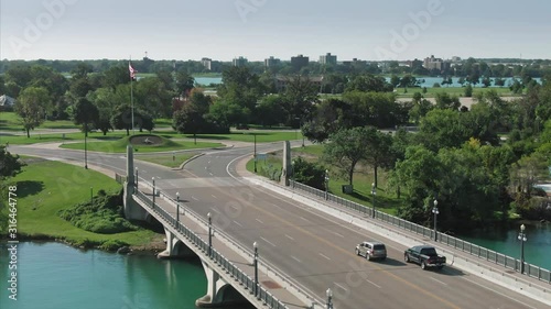 Aerial: Car crossing MacArthur Bridge on the Detroit River on Belle Isle park in Detroit, Michigan,  USA photo