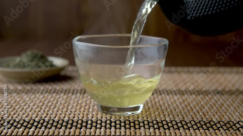 Hot Japanese green tea in glass cup with teapot and leaf
