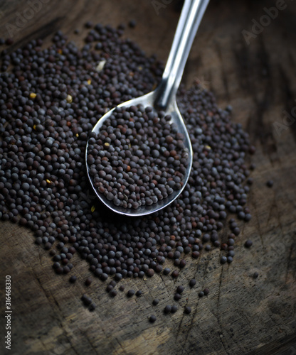 Black mustard seeds on a wooden table