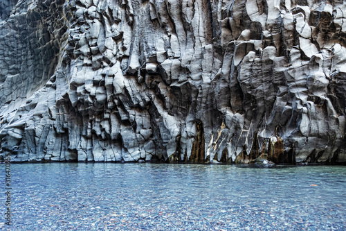 Alcantara Gorge and Alcantara river Park in Sicily island, Italy. Water and Volcanic stones wall.