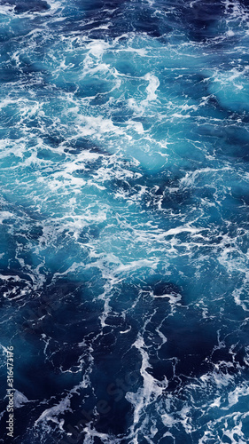 Sea water, white sea foam, water texture, pacific ocean. natural background. foam composition in the dark ocean water