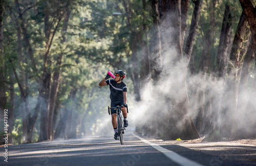 Fototapeta Naklejka Na Ścianę i Meble -  Cyclist is drinking water from the sport bottle