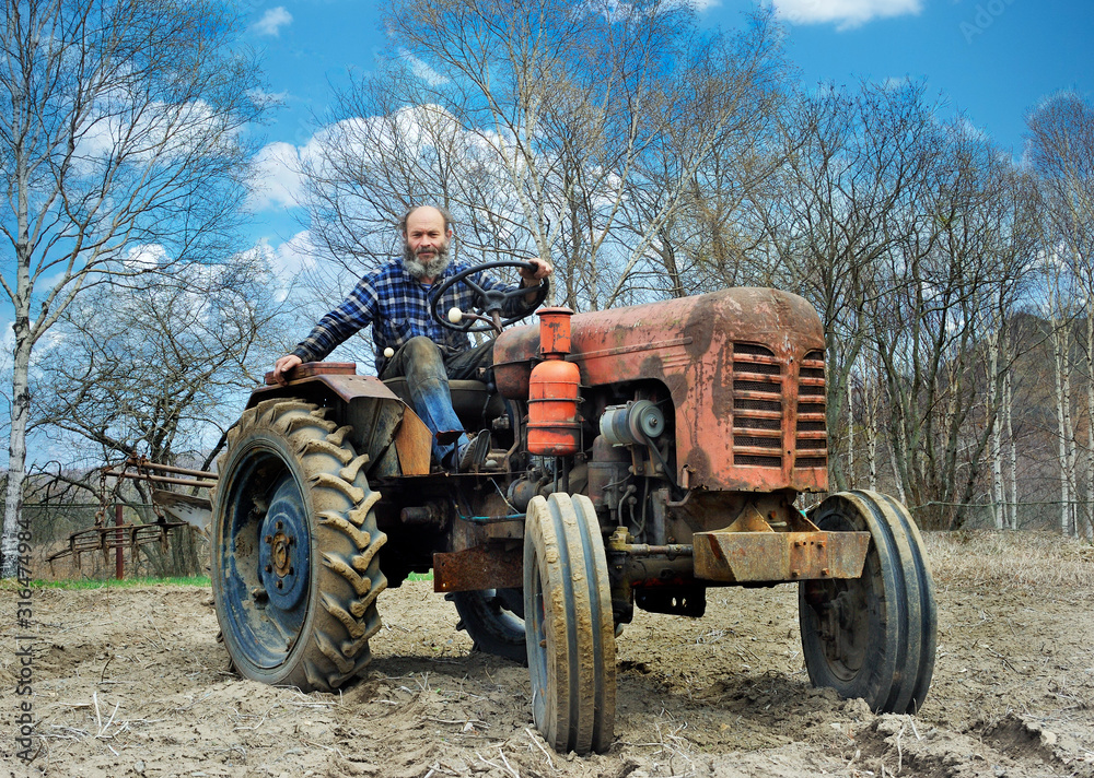 the bearded farmer establishes a plow on a tractor. Tractor on an arable land the bearded farmer establishes a plow on a tractor. Tractor on an arable land