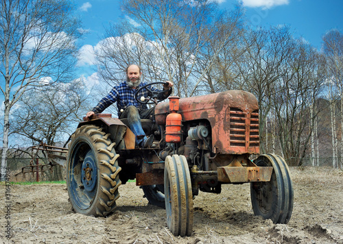 the bearded farmer establishes a plow on a tractor. Tractor on an arable land