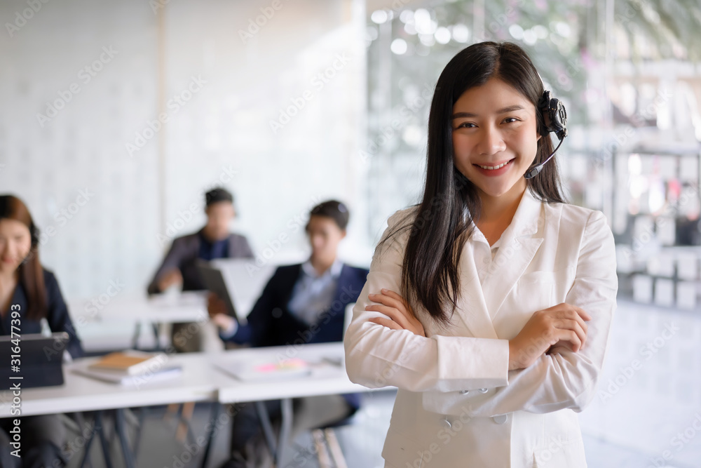 Confident female customer services agent with headset working in a call center office. Customer service team support concept Confident female customer services agent with headset working in a call center office. Customer service team support concept
