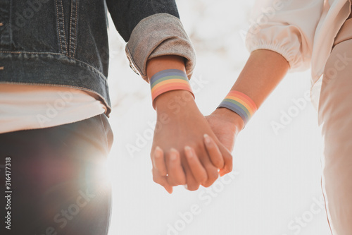 Obraz na plátně Cropped shot of young asian women LGBT lesbian couple holding hands with LGBT pride