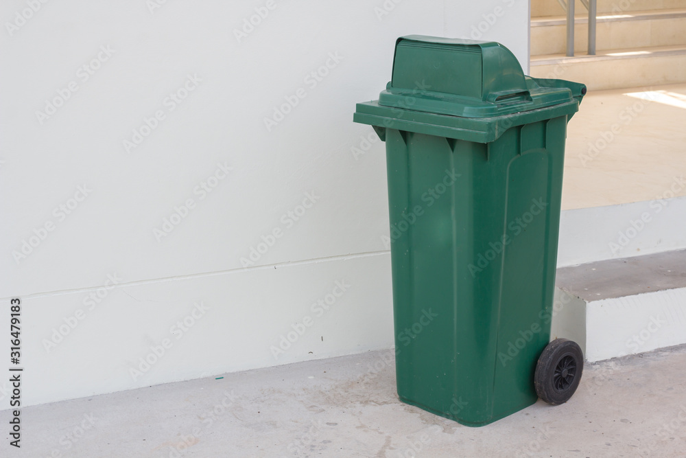 large green wheelie bin for rubbish,Public trash background,Big pile of garbage and waiste in black bags. large green wheelie bin for rubbish,Public trash background,Big pile of garbage and waiste in black bags.