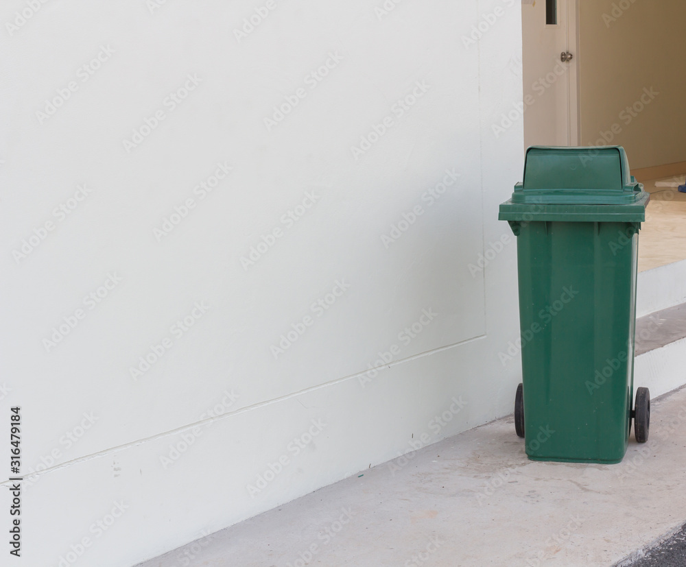 Fototapeta premium large green wheelie bin for rubbish,Public trash background,Big pile of garbage and waiste in black bags.