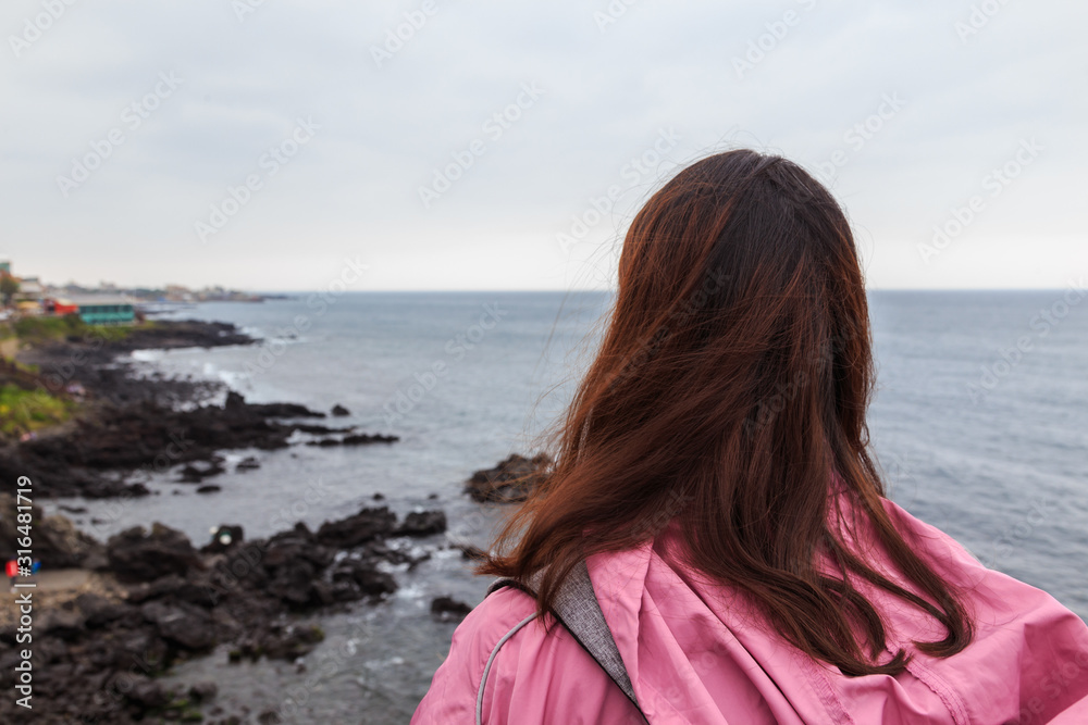 A young lady enjoying the nature scenery at Jeju Yongduam Rock, Jeju Island, South Korea. A young lady enjoying the nature scenery at Jeju Yongduam Rock, Jeju Island, South Korea.