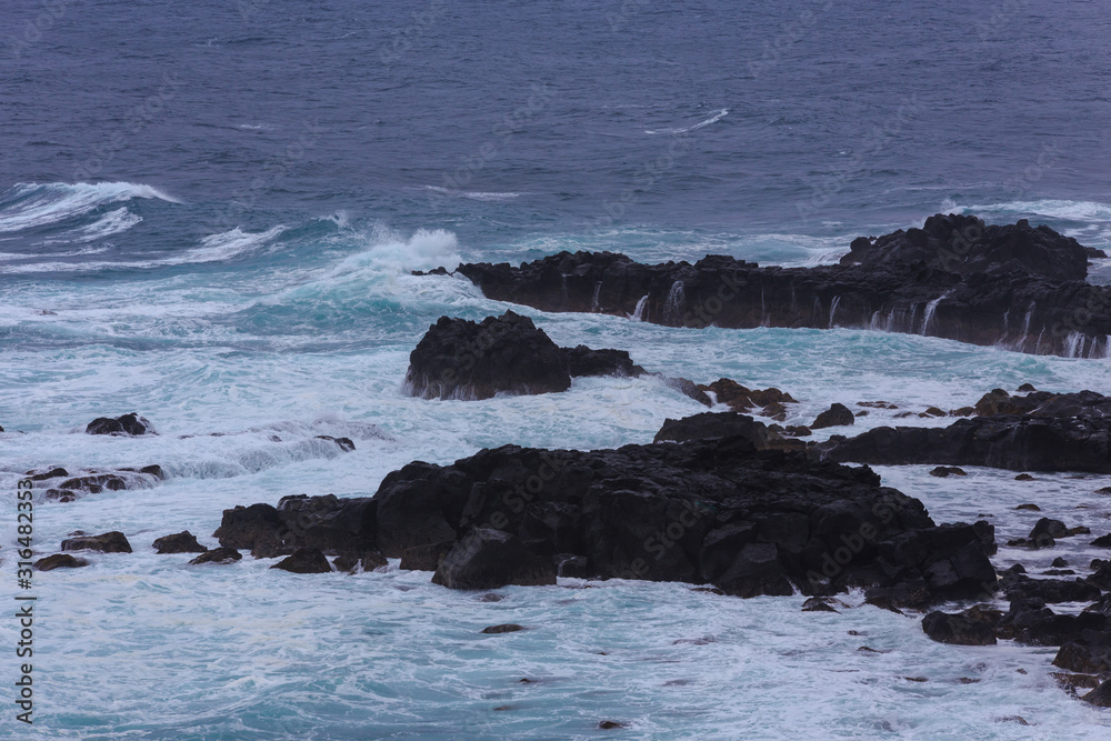 Beautiful Nature scene of sea wave hitting on the black stone shoreline at Jeju Island, South Korea. Beautiful Nature scene of sea wave hitting on the black stone shoreline at Jeju Island, South Korea.