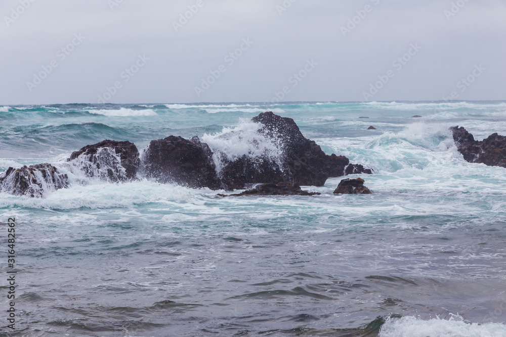 Beautiful Nature scene of sea wave hitting on the black stone shoreline at Jeju Island, South Korea.