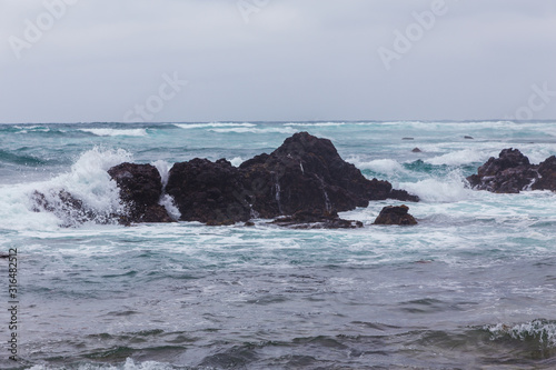 Beautiful Nature scene of sea wave hitting on the black stone shoreline at Jeju Island, South Korea.