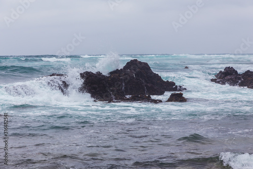 Beautiful Nature scene of sea wave hitting on the black stone shoreline at Jeju Island, South Korea.
