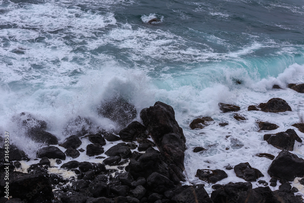 Beautiful Nature scene of sea wave hitting on the black stone shoreline at Jeju Island, South Korea. 