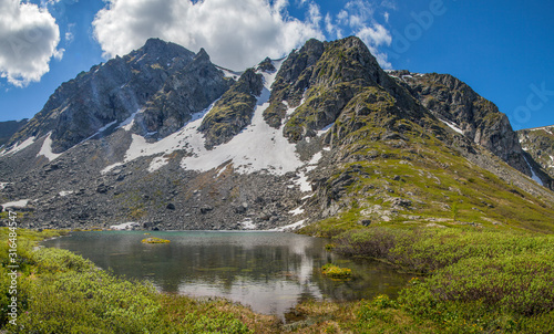 A small mountain lake. Rocky peaks and snowfields. Spring in the mountains.