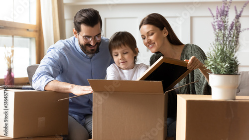 Happy family unpack boxes with little son