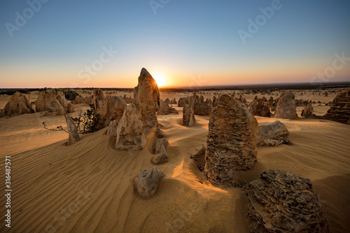 Sun setting behind the limestone stacks in the Pinnacles desert in the Nambung national park located north of Perth in Western Australia photo