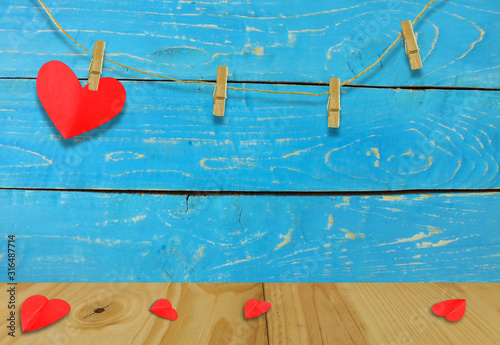 A Valentine's day concept.A red heart shaped card attached to a wooden clip Hanging with hemp rope on wood plate  blue.Valentine's Day background