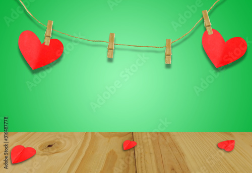 A Valentine's day concept.A red heart shaped card attached to a wooden clip Hanging with hemp rope on pastel  green.Valentine's Day background