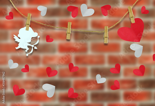 Valentine's day concept.White cupid shaped card attached to a wooden clip Hanging with hemp rope on brick wall .Valentine's Day background
