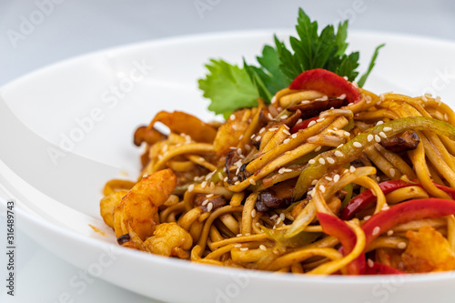 Pan asian food. Wok noodles on a white plate, close up