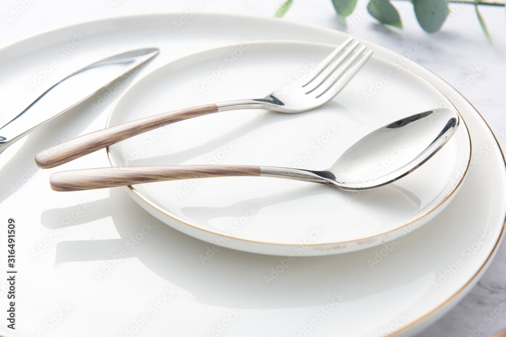 Chopsticks, spoons, knives and forks are arranged on ceramic plates Chopsticks, spoons, knives and forks are arranged on ceramic plates