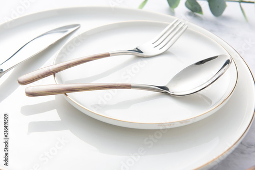 Chopsticks, spoons, knives and forks are arranged on ceramic plates