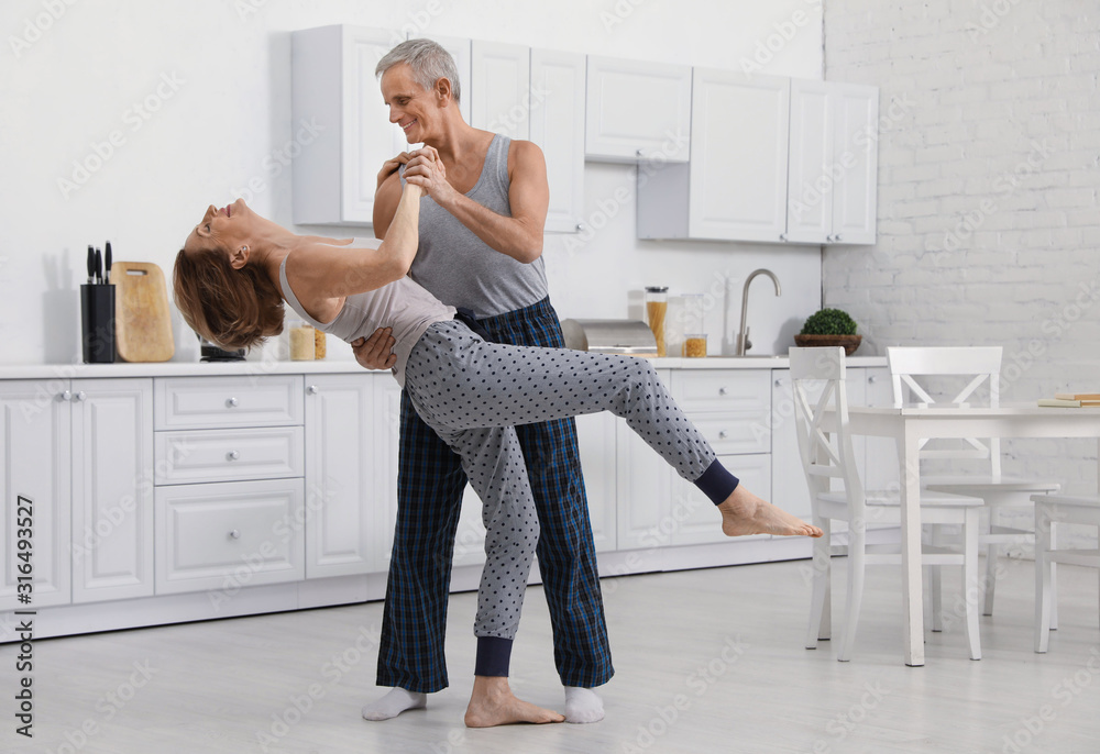 Happy senior couple dancing together in kitchen Happy senior couple dancing together in kitchen