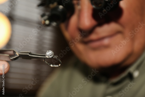 Professional jeweler working with beautiful ring indoors, closeup