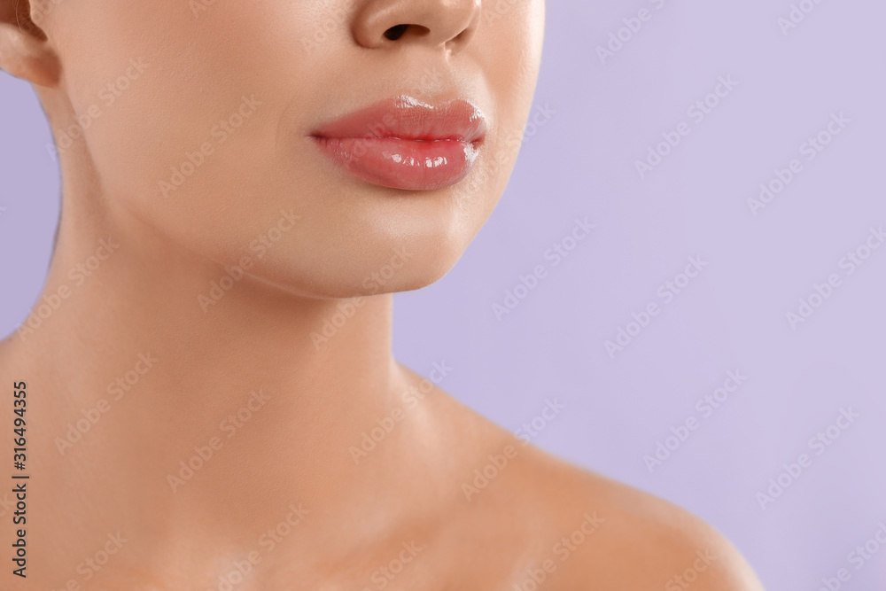 Young woman with beautiful full lips on lilac background, closeup