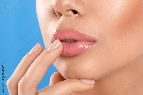 Young woman with beautiful full lips on light blue background, closeup