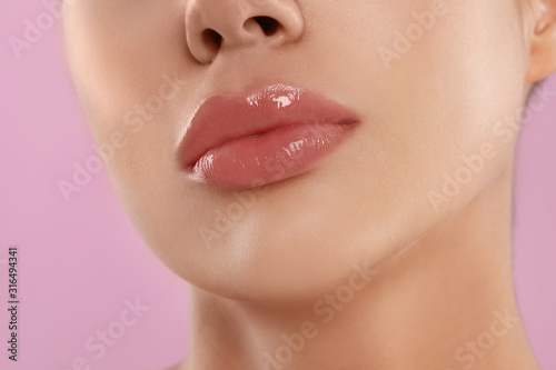 Young woman with beautiful full lips on pink background, closeup photo