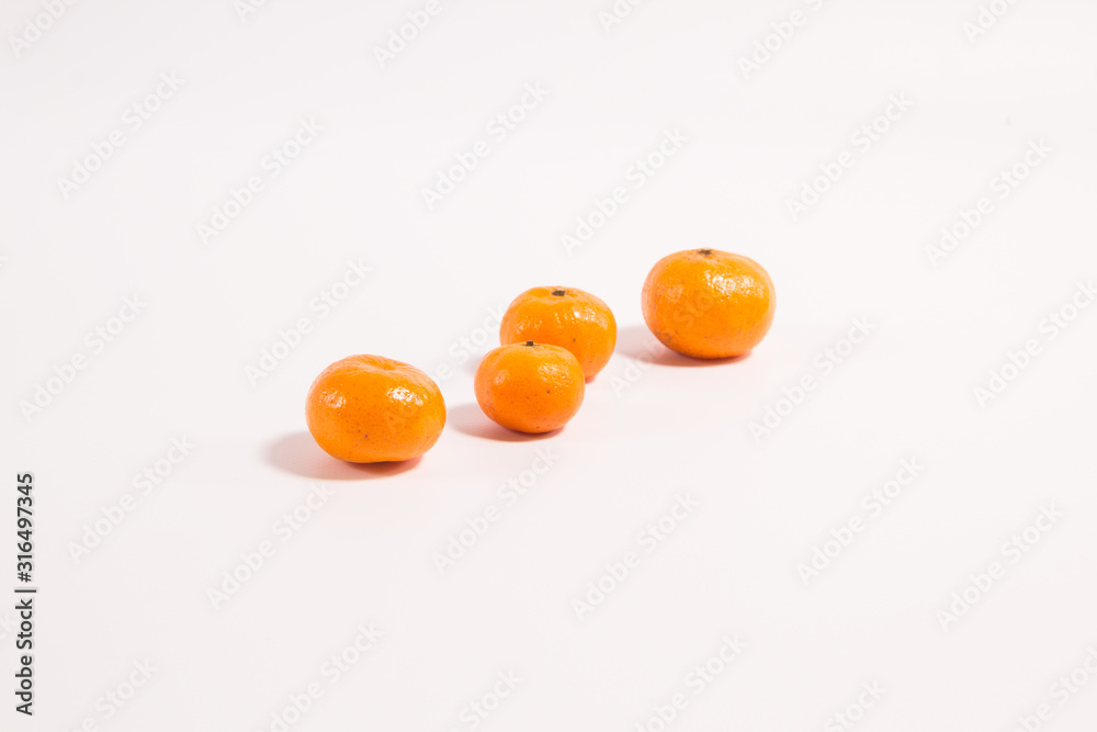 Tangerines on a white background one after another one in the foreground the rest are out of focus Tangerines on a white background one after another one in the foreground the rest are out of focus