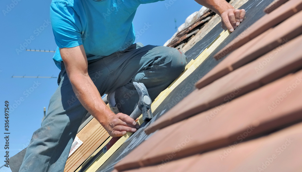 close on a worker holding a hammer and renoving a roof of a house close on a worker holding a hammer and renoving a roof of a house