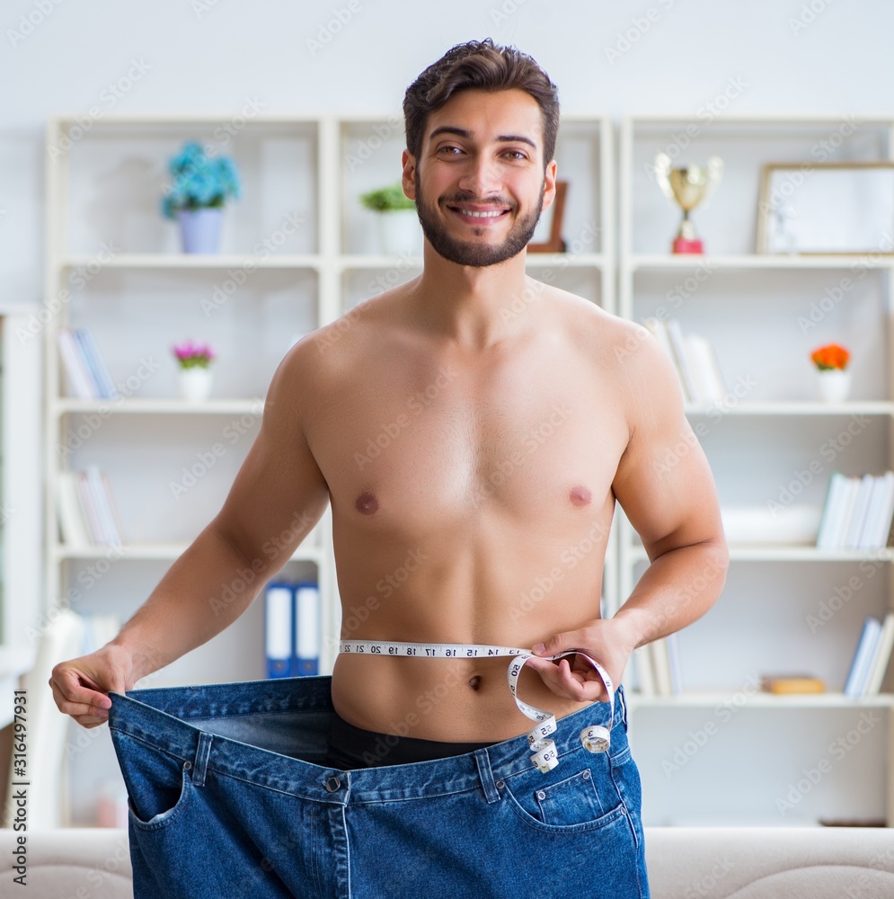 Man in oversized pants in weight loss concept Man in oversized pants in weight loss concept