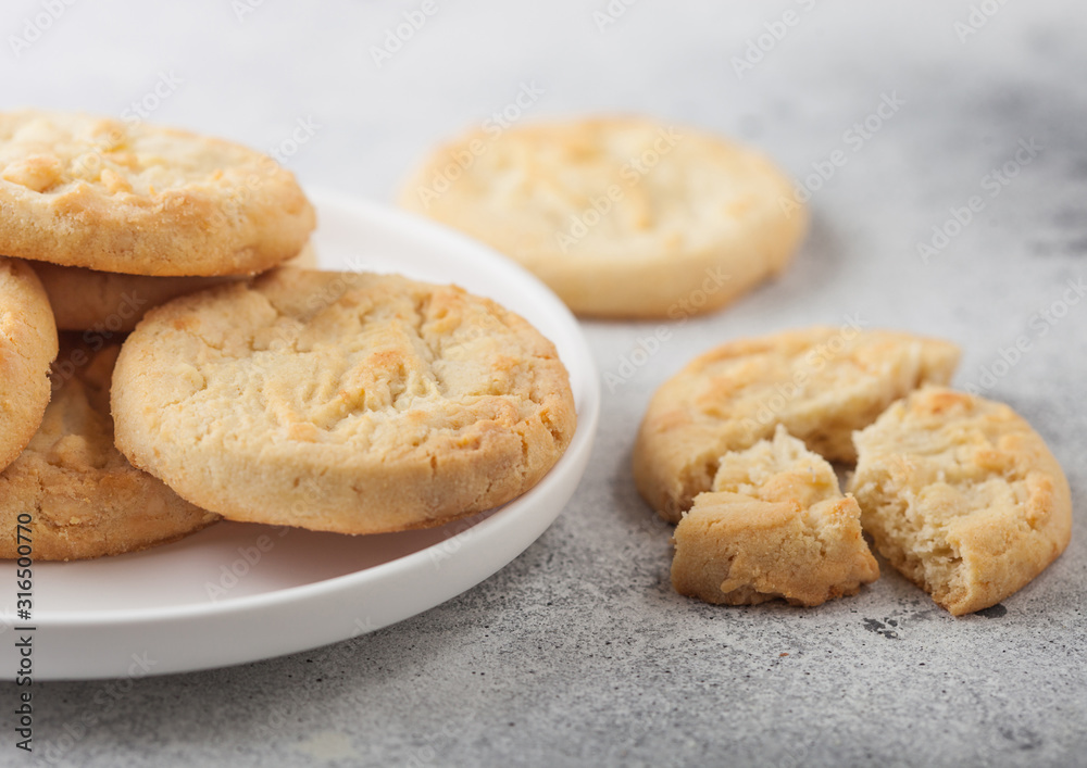 White chocolate biscuit cookies on white ceramic plate on light kitchen table background.