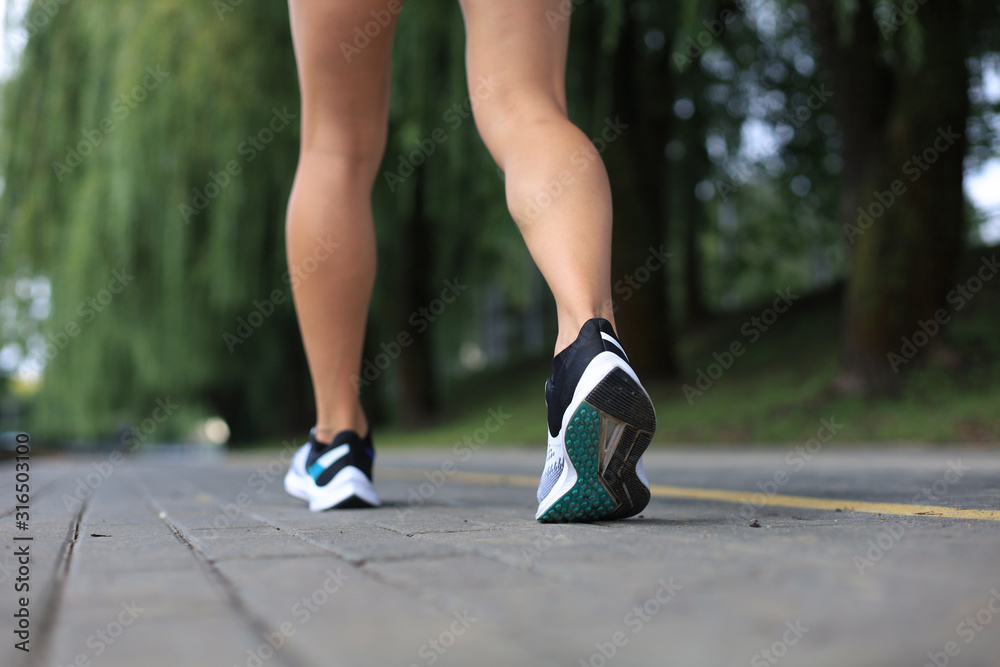 Runner feet running on road closeup on shoe, outdoor at sunset or sunrise.