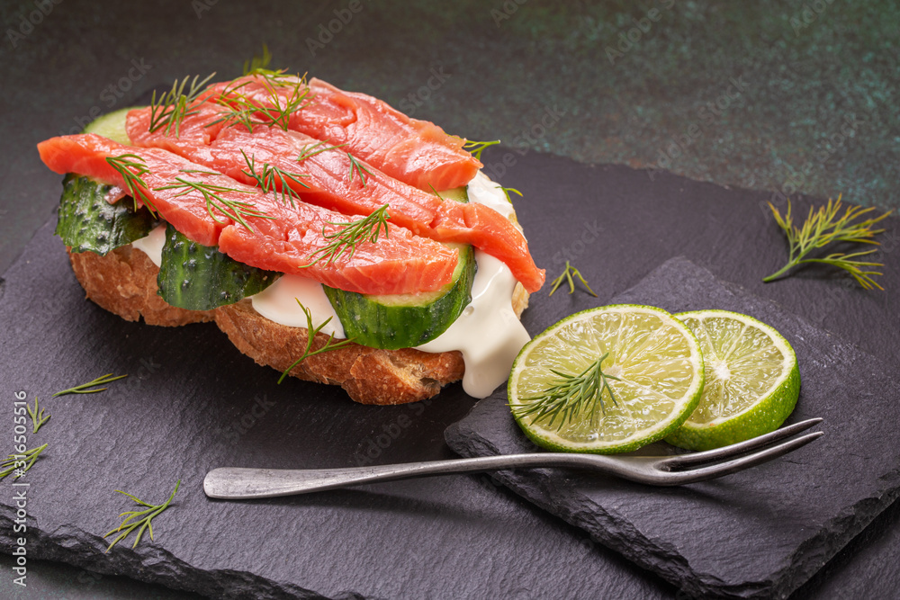 Salted salmon sandwich with cream cheese and cuccumber on slate platter closeup Salted salmon sandwich with cream cheese and cuccumber on slate platter closeup