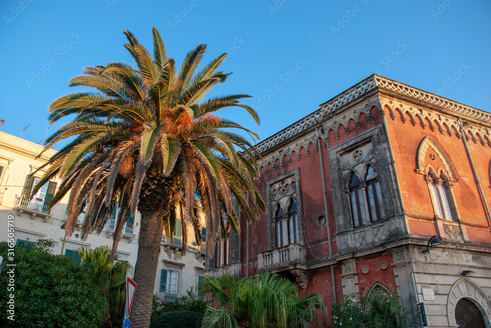Palme vor terracotta farbenem Haus in Syracusa, Sizilien