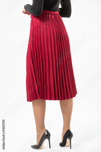 a girl in a red long ruffled skirt and black high heeled shoes isolated on a white background