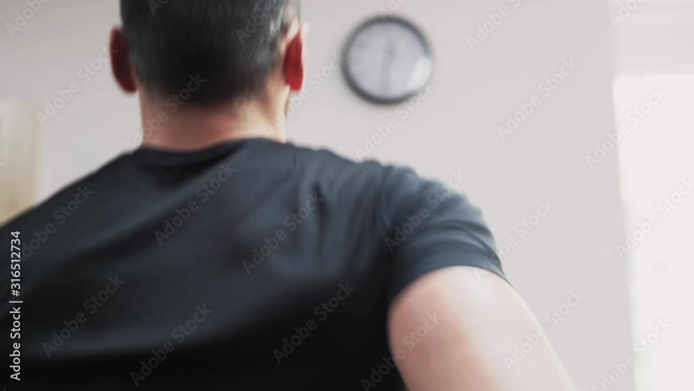 The elder man running on the treadmill back close up shot The elder man running on the treadmill back close up shot