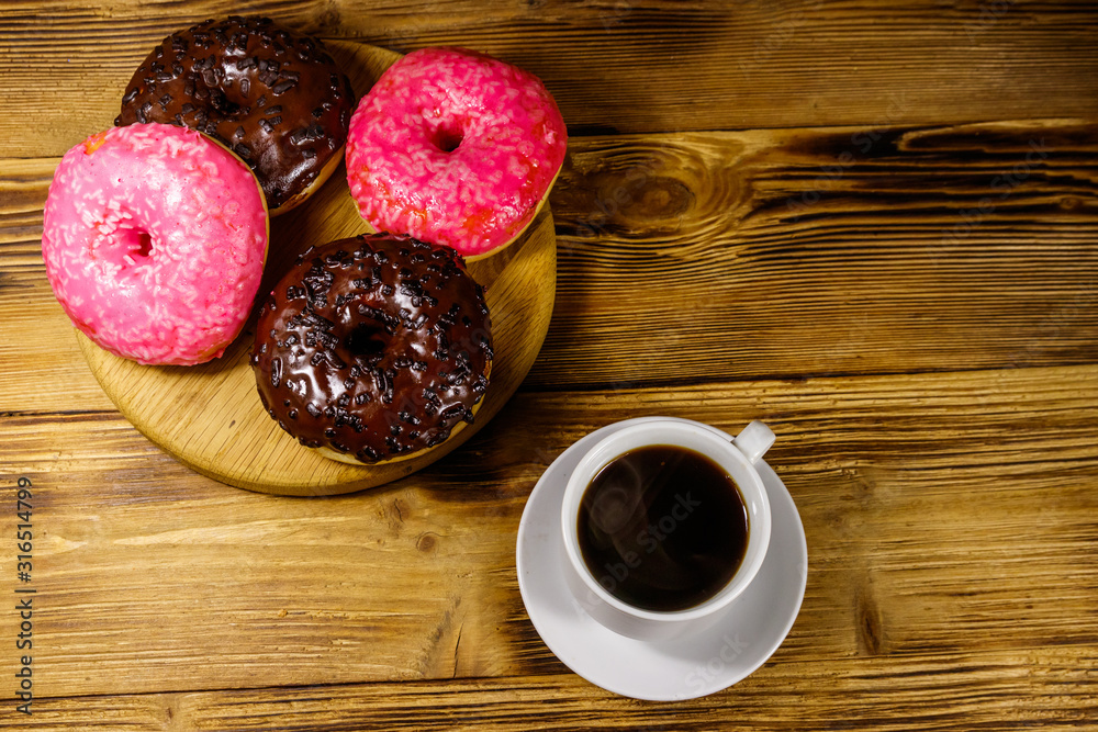 Cup of coffee and tasty donuts on a wooden table. Top view Cup of coffee and tasty donuts on a wooden table. Top view