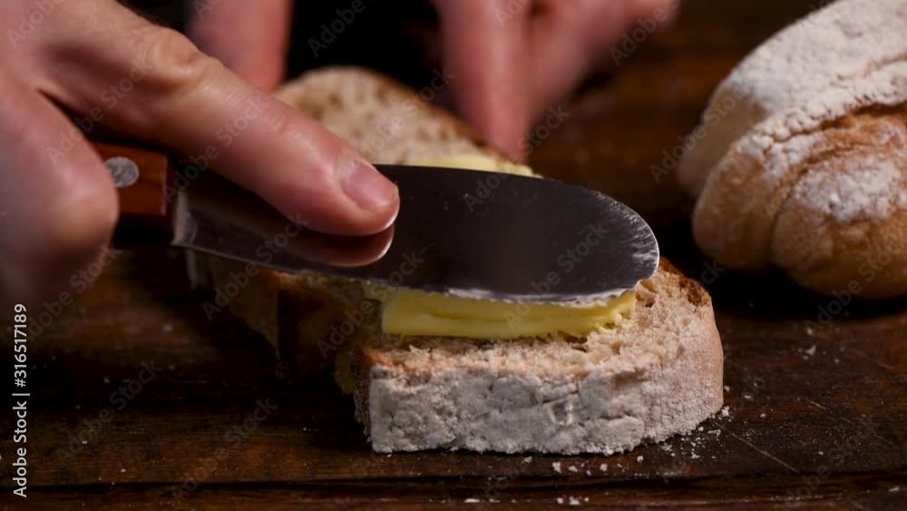 Spreading soft yellow butter on bread. Male hand smear butter on sourdough white bread closeup view Spreading soft yellow butter on bread. Male hand smear butter on sourdough white bread closeup view
