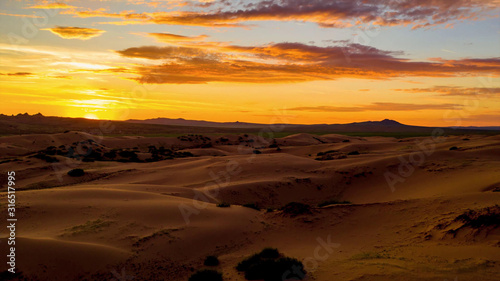 Beautiful sunset in a deserted desert, covering with orange light all around
